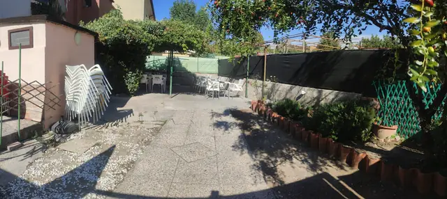 Il giardino del Bar Buffet al Gatto Nero, con il vialetto, le aiuole e i tavoli sotto il pergolato