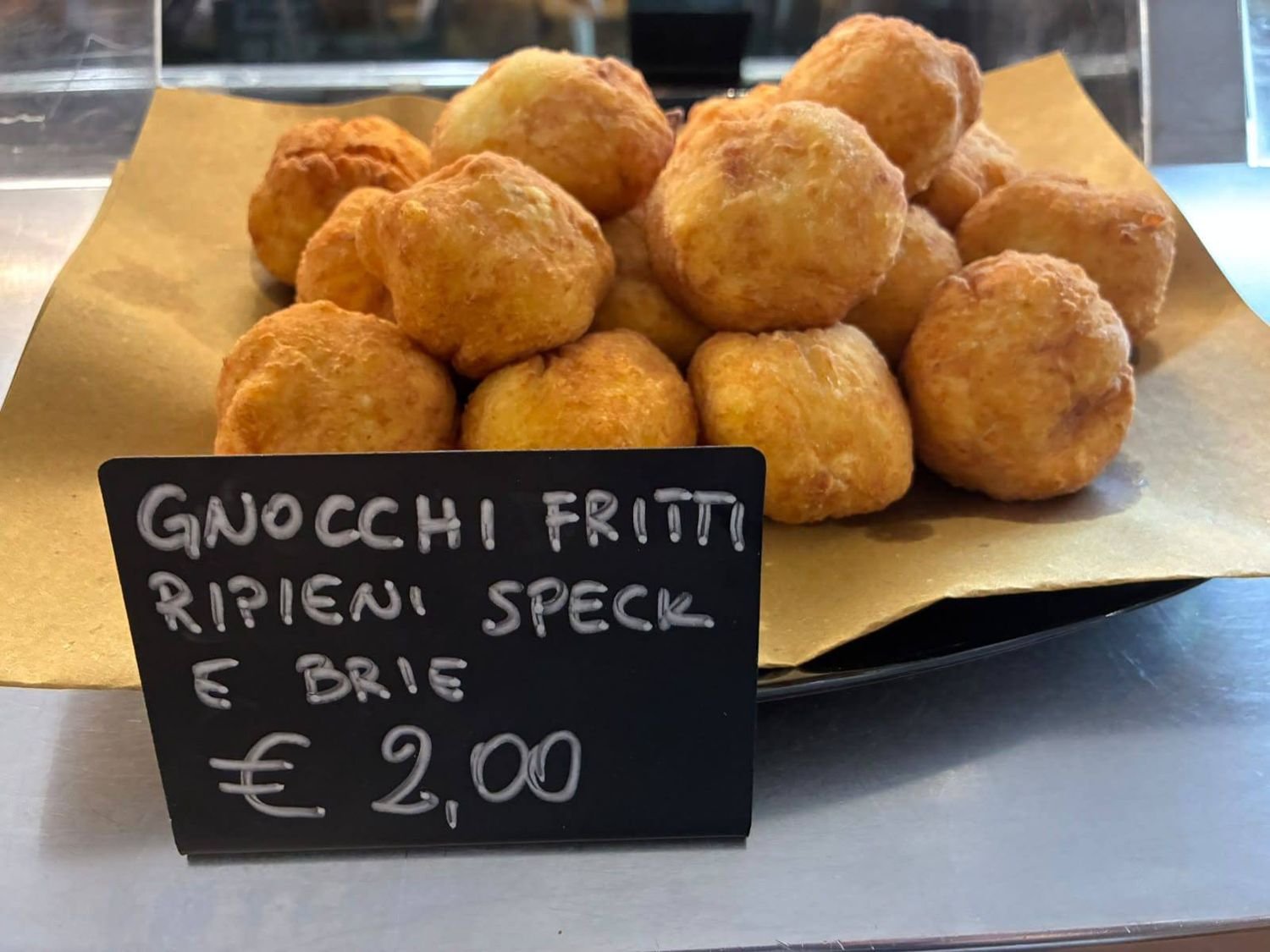 Gnocchi fritti ripieni di speck e brie con il cartello del prezzo in vetrina