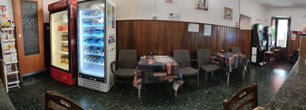 La sala interna del bar con i tavoli, la boiserie in legno e il pavimento in graniglia
